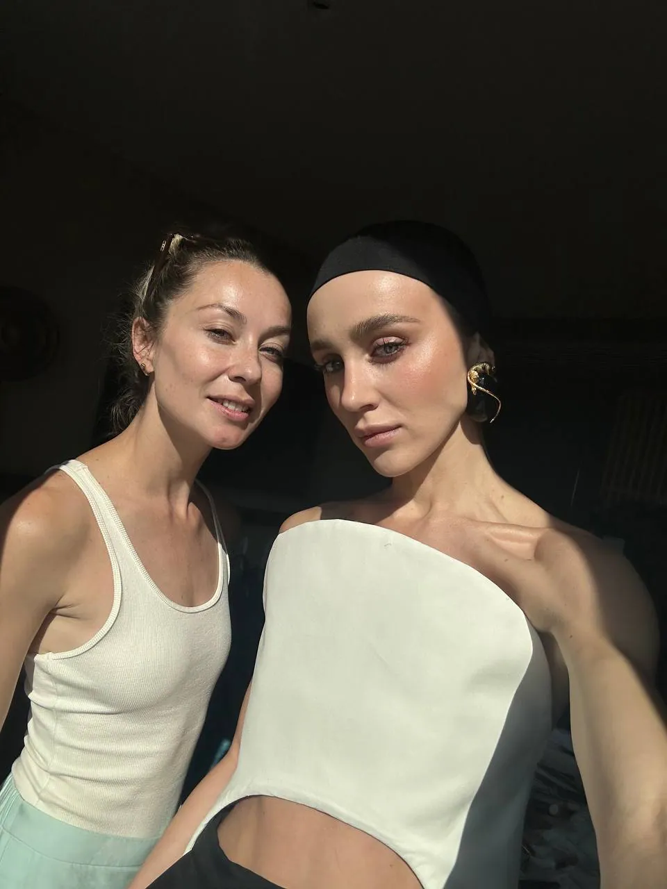Екатерина рядом с моделью в чёрной повязке и белом платье на солнце