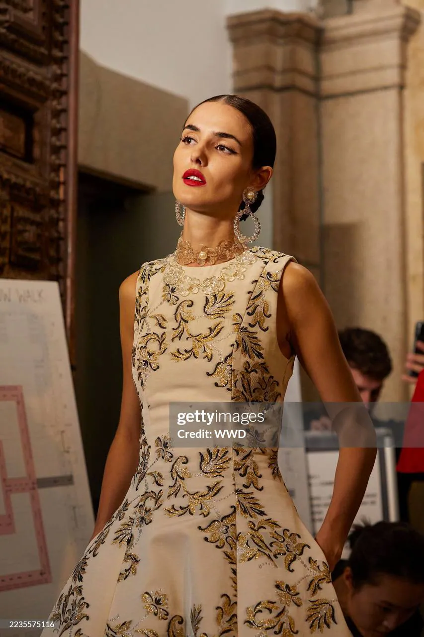 Модель в бежевом платье с золотой вышивкой за кулисами показа Carolina Herrera